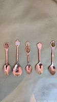 Front view of all five silver-plated souvenir spoons