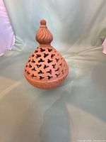 Full view of terracotta pierced lantern showing shape and finial.