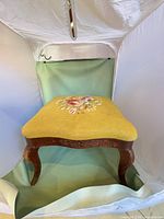 Full view of footstool showing upholstery and wood frame