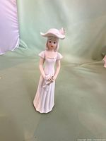Front view of white porcelain lady figurine in gown and hat