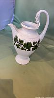 Full view of porcelain pitcher showing shape, handle, footed base, and leaf decoration