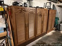 Four brown louvered-door cabinets side by side in basement
