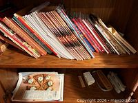 Shelf with large stack of cooking magazines and thin cookbooks, plus recipe card packet