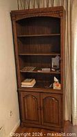 Full view of pantry cabinet angled, doors closed, showing open shelving and lower doors