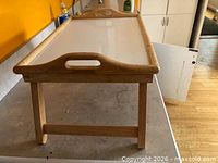 Folding tray standing on legs, showing handle cut-outs and frame