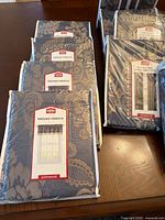 Stacked packaged valances and curtains showing labels and pattern