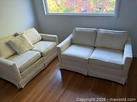 Two matching white sleeper sofas side by side with pillow visible