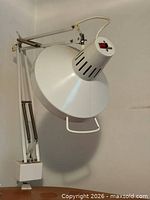 Side view of white clamp-on adjustable arm desk lamp mounted to surface
