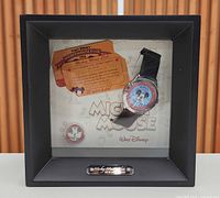 Front view of display box containing watch, pin and certificate