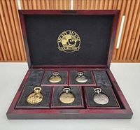 Open wooden case showing five pocket watches in fitted slots