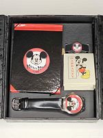Open presentation box showing watch, pin, notebook, warranty booklet