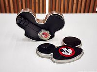 Watch inside open Mickey head-shaped tin with detached lid visible