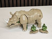 Full view of Rhinox figure in rhino mode with two green blasters beside