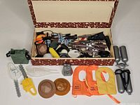Overall lot view with open box showing weapons and accessories, loose items arranged in front