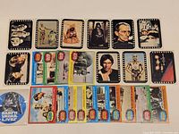 Assortment of black film-border cards, coloured-border cards and promo sticker laid out on surface