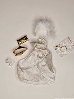All outfit components laid out: dress, belt, clutch, shoes, feather plume, jewellery