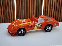 Left side view of orange Corvette toy showing decals and wheels