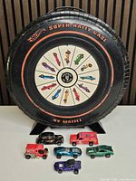 Front view of tire-shaped Super Rally case with six Hot Wheels cars arranged in front