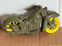 Left side view of olive plastic motorcycle with yellow wheels