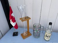Full lot showing flag, tall beer glass on stand, Moosehead mug and Liquormen’s whisky bottle
