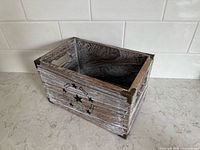 Angled view of wooden box showing whitewashed slats and interior