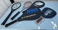 All five racquets laid out on table showing brands, covers and grips
