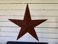 Front view of brown metal five-point star on white wall