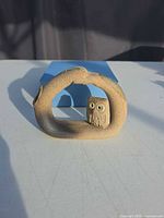 Front view of stoneware arch bud vase with owl inset; box in background