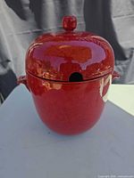 Front view of red ceramic jar with lid showing ladle notch and glossy finish