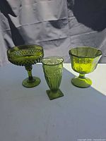 Front view showing three green pressed glass footed pieces