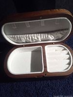 Box open showing interior compartments, ring slots, elastic lid pouch