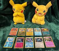 Ten holographic Pokémon cards laid out; Pikachu plush toys behind (not for sale)