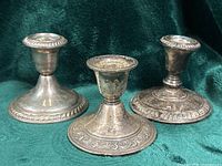 Front view of three unmatched sterling silver candlesticks