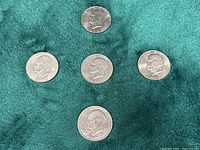 Five Eisenhower dollars arranged on green fabric