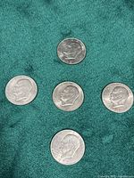 Five Eisenhower dollars spread on green fabric