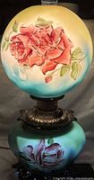 Overall view of lamp lit, showing hand-painted roses on upper and lower globes