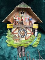 Front view of chalet cuckoo clock showing figures, dial and case details