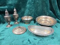 All six silver-plated pieces displayed on green fabric