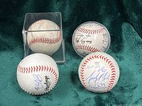 Front view of four autographed baseballs, two purportedly in cases