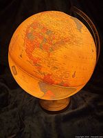 Globe illuminated showing North and South America on wood base with power cord
