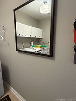 Front angled view of square wall mirror on wall
