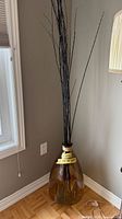 Full view of glass floor vase with tall black branches