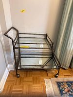 Full view of faux bamboo metal serving cart showing two glass shelves and handle
