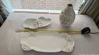 Overall view of all three porcelain pieces with measuring tape for scale