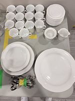 Overall view of dinnerware set with mugs, saucers, plates, serving pieces and spoons