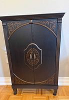 Front view of closed cabinet showing gold embellishments and double doors