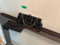 Both clutches on display; beaded clutch shows chain strap and metal frame, fabric clutch closed