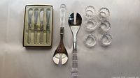 overview of all items: boxed butter knives, two salad servers, six napkin rings