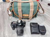 Complete lot showing camera with lens, flash with case, and Canon green bag
