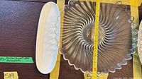 White ceramic dish alongside clear swirl glass bowl with measuring tape showing dimensions